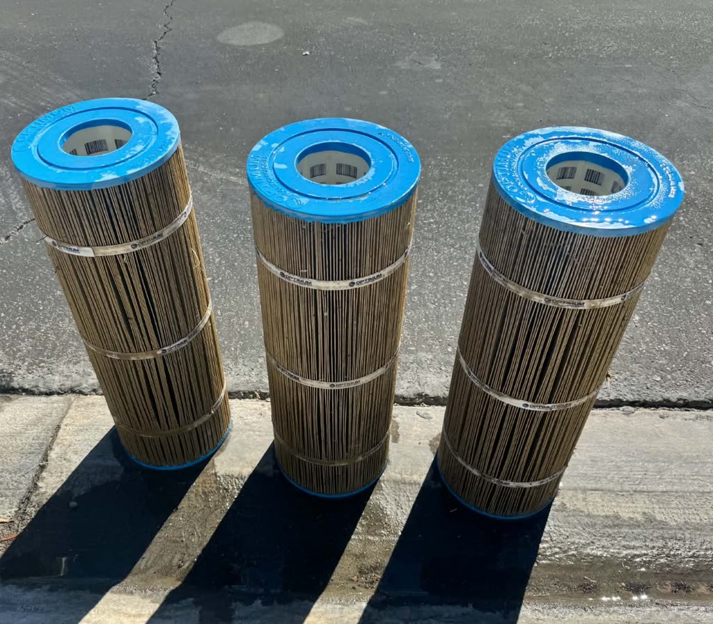 Pool filter cartridges before cleaning, the pleats packed with grey-brown debris.